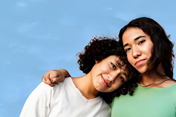 Two teen girls: one is resting her head on the other girls shoulder