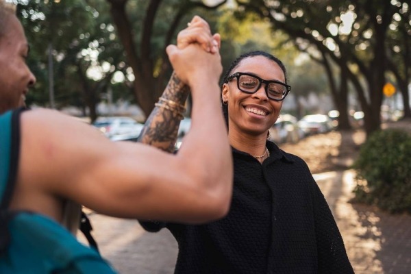 Group of diverse friends great each other and clasp hands while standing in a park.