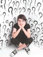A photo of a girl sitting in a white room with question marks all over the walls.