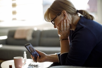 Mature woman talking with a doctor during a video telehealth appointment on her phone.