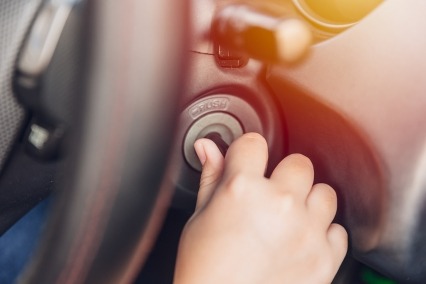 Closeup of hand twist turn car key to start ignite engine for drive.