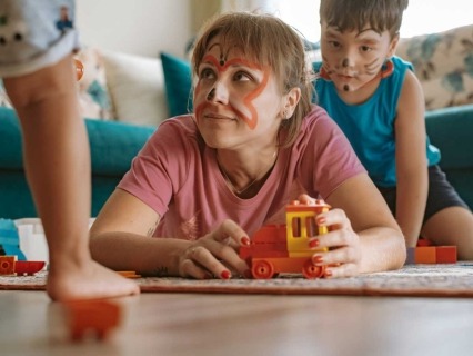 Mother playing on the floor with two young children.